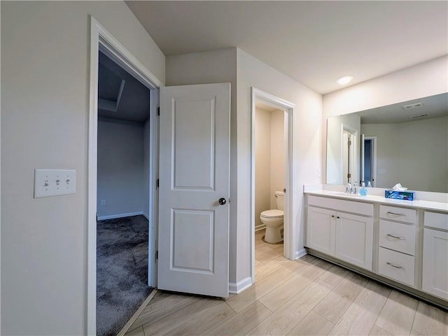 bathroom with wood finished floors, toilet, vanity, and baseboards