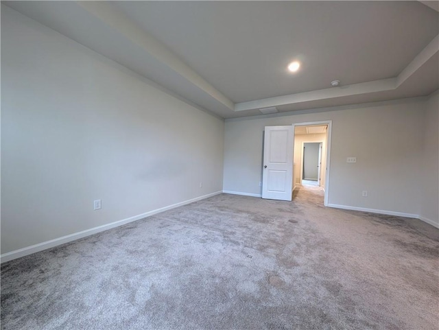 unfurnished room featuring a tray ceiling, baseboards, and carpet floors
