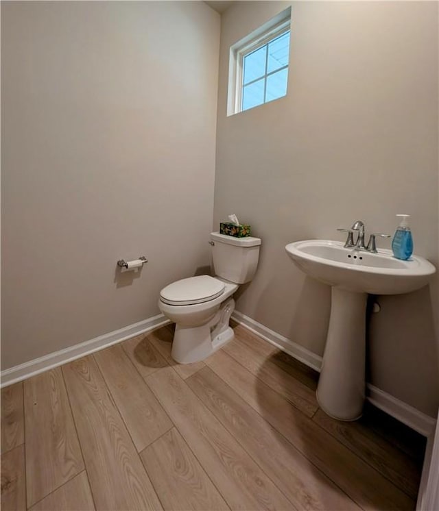 half bath featuring toilet, wood finished floors, and baseboards