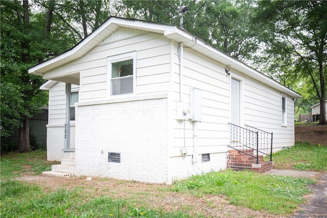 view of property exterior with crawl space, entry steps, and brick siding