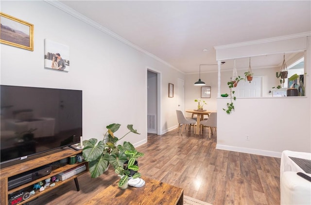 living area featuring wood finished floors, baseboards, and crown molding