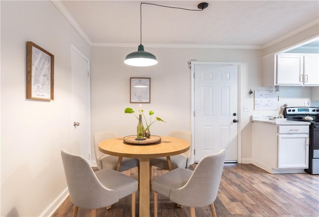 dining area with light wood-style flooring, baseboards, and crown molding