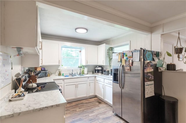 kitchen featuring stainless steel fridge with ice dispenser, a sink, ornamental molding, light countertops, and white cabinetry