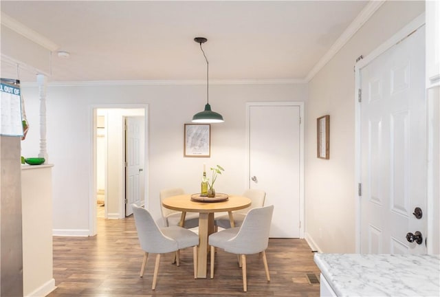 dining room featuring dark wood-style flooring, crown molding, and baseboards