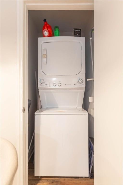 washroom with stacked washer and clothes dryer and wood finished floors