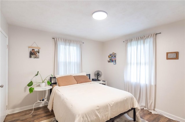 bedroom with dark wood-style floors and baseboards