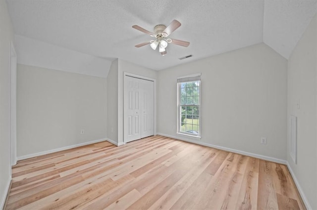 unfurnished bedroom featuring wood finished floors, baseboards, a closet, vaulted ceiling, and a ceiling fan