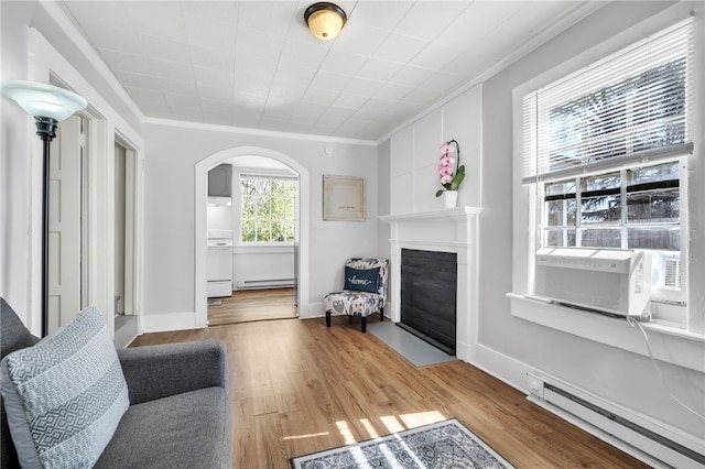 60 N Humphrey St, Inman, SC 29349 - living room with baseboard heating, ornamental molding, arched walkways, a fireplace with flush hearth, and wood finished floors