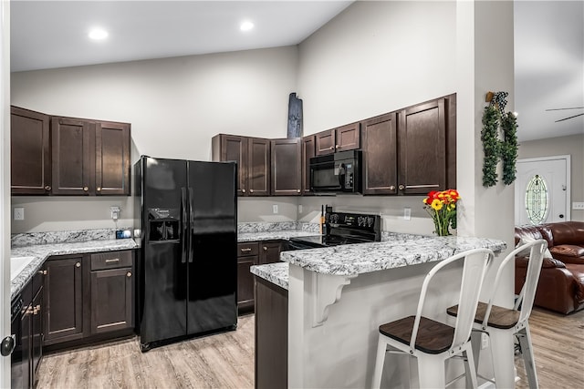600 Brook St, Honea Path, SC 29654 - kitchen featuring black appliances, dark brown cabinetry, light wood-style flooring, a peninsula, and high vaulted ceiling