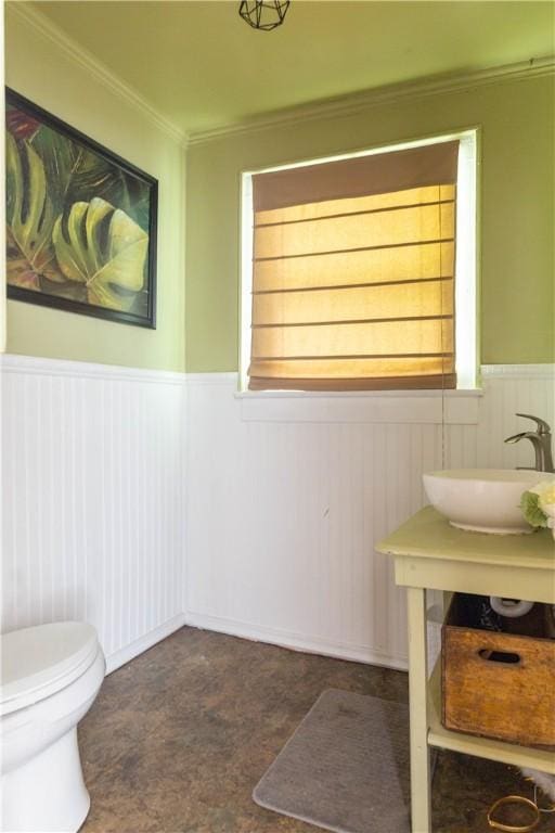 bathroom with wainscoting, a sink, crown molding, toilet, and tile patterned floors