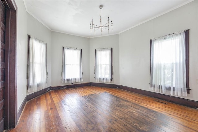 unfurnished room with a chandelier, hardwood / wood-style flooring, crown molding, and baseboards