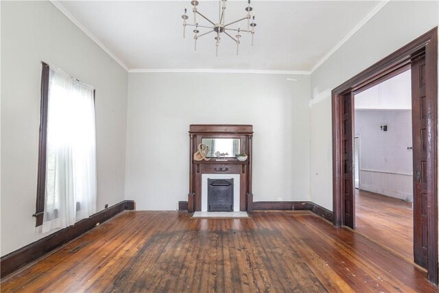 unfurnished living room with wood-type flooring, a chandelier, ornamental molding, and a fireplace