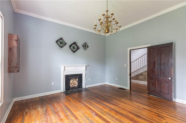 unfurnished living room with ornamental molding, wood finished floors, a chandelier, baseboards, and stairway