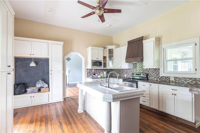 kitchen featuring appliances with stainless steel finishes, ceiling fan, backsplash, a sink, and dark wood-style floors