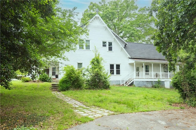 rear view of house with a porch, a yard, stairway, and a shingled roof