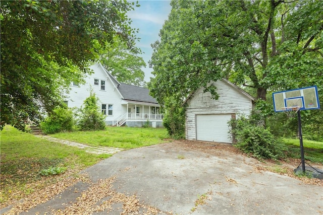 view of front of house with an outbuilding, driveway, a garage, a front yard, and a porch