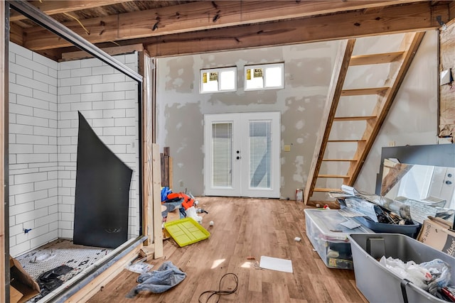 below grade area featuring wood finished floors, stairs, and french doors