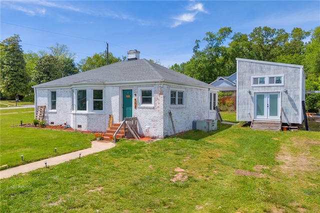 rear view of house with a yard, crawl space, brick siding, a chimney, and entry steps