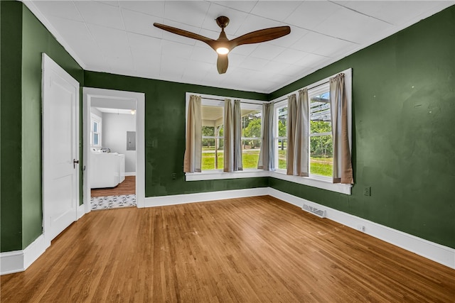unfurnished room with wood finished floors, baseboards, a ceiling fan, and ornamental molding