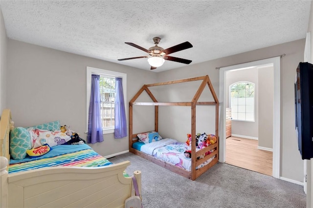 carpeted bedroom with baseboards, ceiling fan, and a textured ceiling