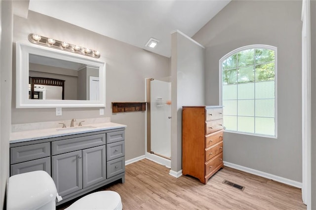 bathroom with wood finished floors, vanity, a shower stall, baseboards, and vaulted ceiling