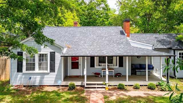 view of front of home featuring an outdoor hangout area, a shingled roof, a chimney, and fence