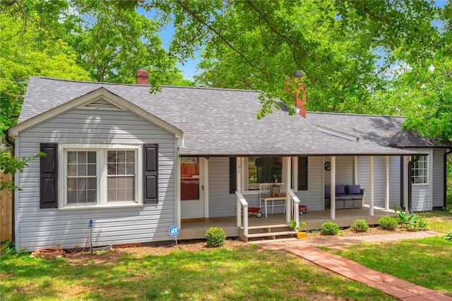 view of front of home with a chimney, a front lawn, and covered porch