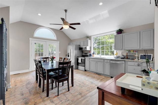 dining room featuring vaulted ceiling, ceiling fan, light wood finished floors, plenty of natural light, and french doors