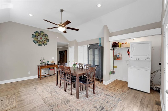 dining area featuring estacked washer and dryer, lofted ceiling, ceiling fan, wood finished floors, and baseboards