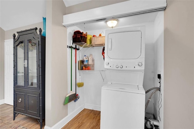 washroom featuring estacked washer and dryer, wood finished floors, and baseboards