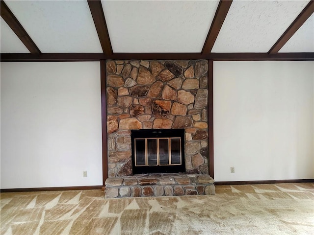 unfurnished living room with beam ceiling, carpet, baseboards, and a stone fireplace