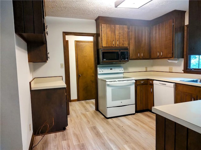 kitchen featuring white appliances, light wood-style flooring, light countertops, and a textured ceiling