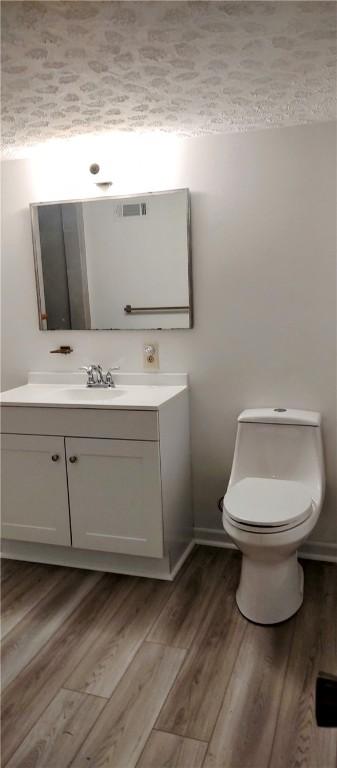 bathroom featuring vanity, wood finished floors, toilet, and baseboards