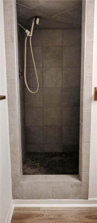 full bath with a shower stall, wood finished floors, and baseboards