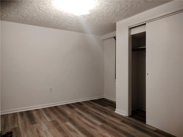 unfurnished bedroom featuring a textured ceiling, wood finished floors, a closet, and baseboards