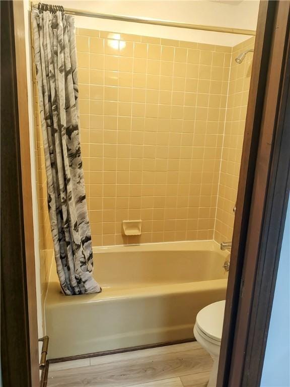 bathroom featuring shower / bath combination with curtain, toilet, and wood finished floors