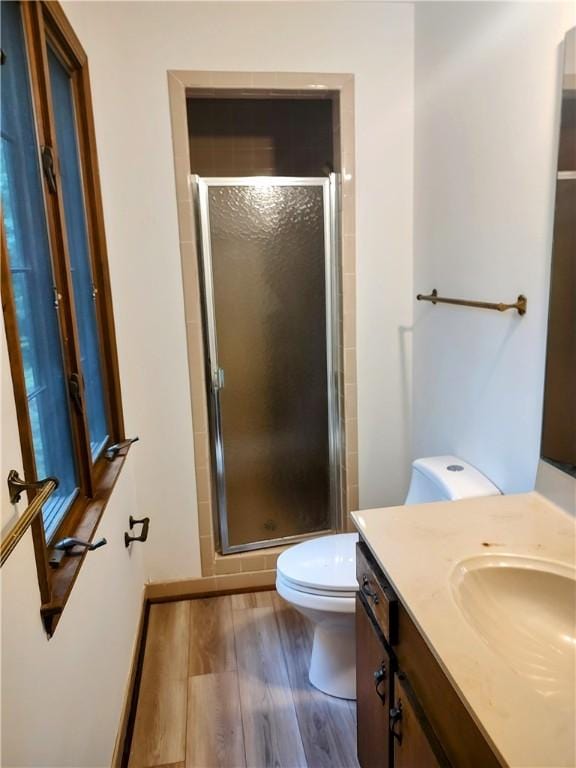 full bath with a shower stall, wood finished floors, toilet, and vanity
