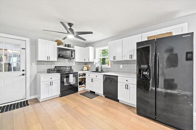 kitchen with black appliances, a sink, white cabinetry, light countertops, and a textured ceiling