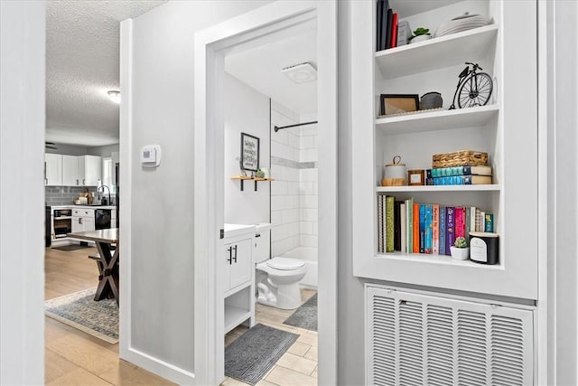bathroom featuring a shower, toilet, a textured ceiling, vanity, and decorative backsplash