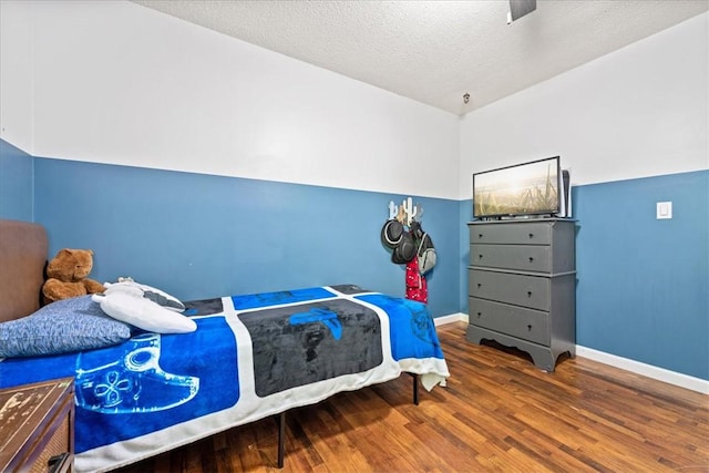bedroom with baseboards, wood finished floors, ceiling fan, and a textured ceiling
