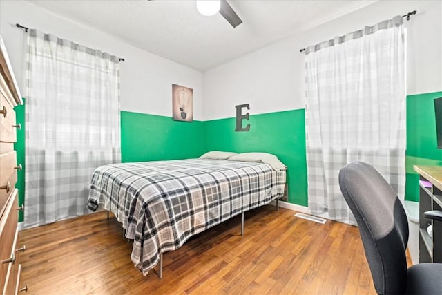 bedroom with wood finished floors, a ceiling fan, and a desk