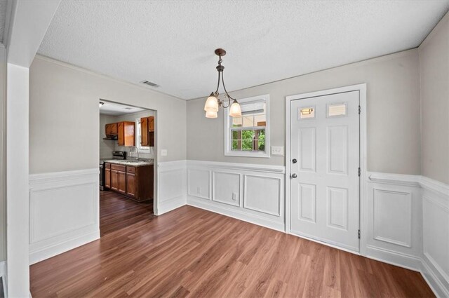 1922 Dobbins Ave, Anderson, SC 29625 - unfurnished dining area featuring dark wood-style flooring, a sink, wainscoting, a textured ceiling, and a decorative wall