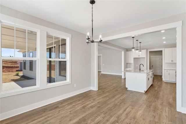 1002 Princeton Rd, Williamston, SC 29697 - kitchen with a chandelier, a sink, baseboards, wood finished floors, and white cabinetry