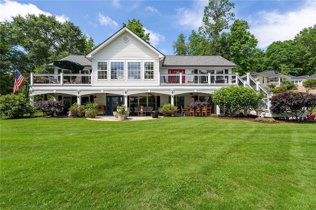 rear view of house featuring a patio, a lawn, stairway, a wooden deck, and roof with shingles