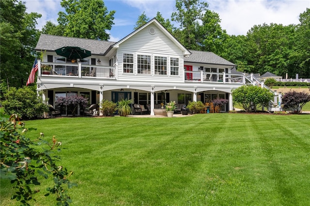 back of property featuring a balcony, a patio area, and a lawn