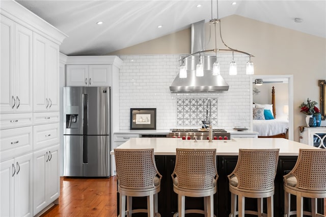 kitchen featuring stainless steel fridge, lofted ceiling, light countertops, wood finished floors, and tasteful backsplash