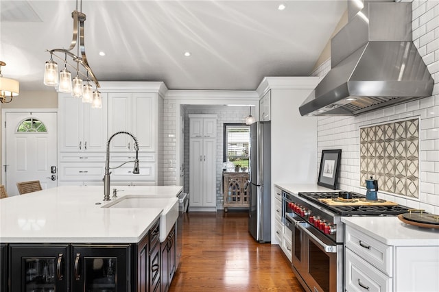 kitchen featuring appliances with stainless steel finishes, wall chimney exhaust hood, light countertops, backsplash, and white cabinetry