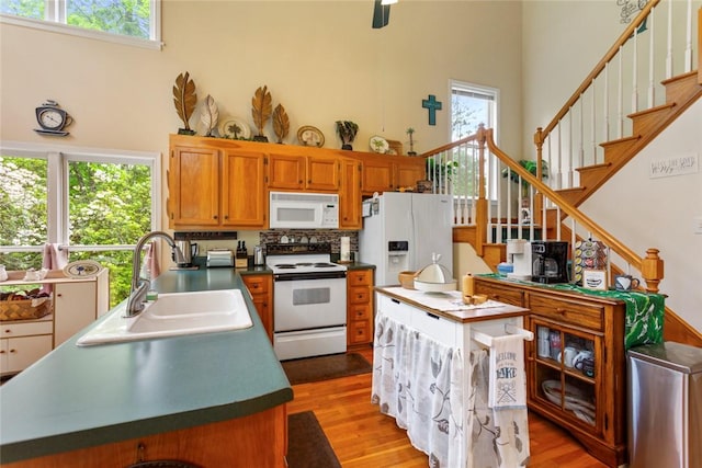 310 Fernwood Dr, Salem, SC 29676 - kitchen with white appliances, a towering ceiling, a sink, light wood-type flooring, and brown cabinetry