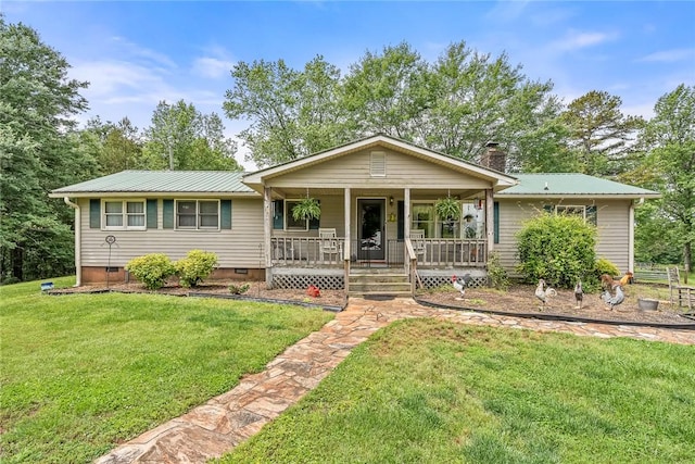 ranch-style home featuring a porch, metal roof, a front yard, and a chimney