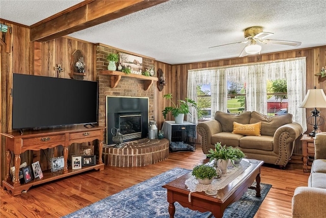 living area with wooden walls, a textured ceiling, ceiling fan, wood finished floors, and ornamental molding